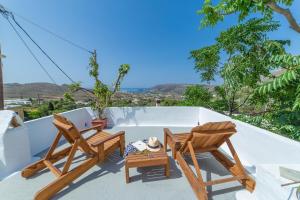 a balcony with two chairs and a table at Andros Melissari in Koumárion