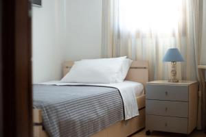 a bedroom with a bed and a lamp and a window at Andros Melissari in Koumárion
