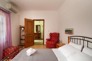 a bedroom with a bed and a red chair at Andros Melissari in Koumárion