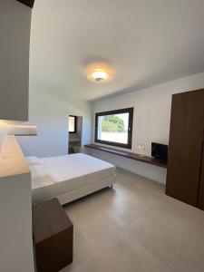 um quarto branco com uma cama e uma janela em Domo La Vela em Cala Liberotto