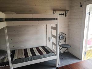 a bunk bed in a wooden room with a chair at Mäentaustan aitat in Janakkala