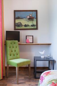 a bedroom with a green chair and a table at Hotel Logis Beauséjour in Erquy