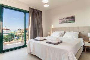 a bedroom with a white bed with a large window at Villa Eden with Private Pool in Gouves