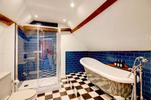 a bathroom with a tub and a toilet and blue tiles at Green Parrot House in Devizes