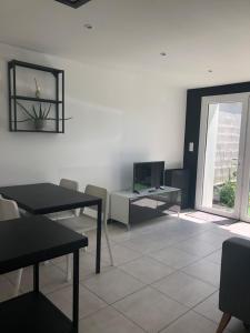 een woonkamer met een tafel en een tv bij Dar Lila Cote d'Opale in Saint-Martin-Boulogne