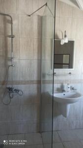 un bagno con lavandino e doccia con porta in vetro di Riverside villas a Ortaca