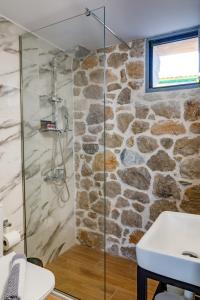 baño con ducha a ras de suelo junto a una pared de piedra en ADRIAN'S LUXURY APARTMENTS 1, en Dhrepanon