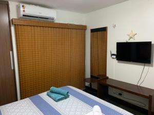 a bedroom with a bed and a tv on a wall at Cumbuco Eco Paradise apto com varanda in Cumbuco