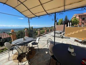 a patio with tables and chairs and an umbrella at Abbazia delle Sorelle in Novello