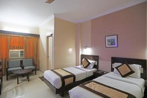 um quarto de hotel com duas camas e uma cadeira em Hotel The Tourist - 1 min from New Delhi Railway Station em Nova Deli
