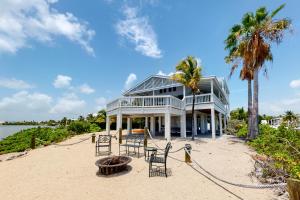 a house on the beach with chairs and palm trees at Hawkins Lookout in Cudjoe Key