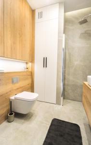 La salle de bains est pourvue d'une douche et de toilettes blanches. dans l'établissement Apartament Voila, à Varsovie