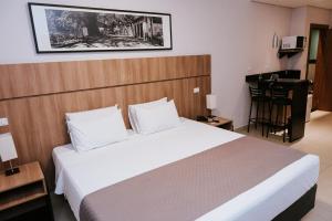 a bedroom with a large bed and a desk at Occitano Apart Hotel in Piracicaba
