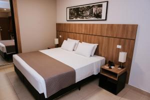 - une chambre avec un grand lit et une tête de lit en bois dans l'établissement Occitano Apart Hotel, à Piracicaba
