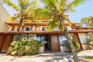 a building with two palm trees in front of it at Pousada La Plage Peró in Cabo Frio