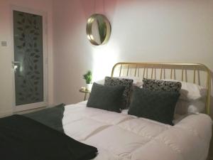 un letto bianco con cuscini neri e specchio di 19, Luqa Townhouse a Luqa