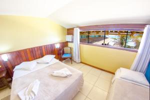 a hotel room with two beds and a window at Pousada La Plage Peró in Cabo Frio