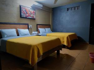 two beds in a hotel room with yellow sheets at Hotel El Paraiso in Xilitla