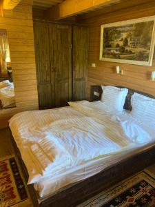 a large white bed in a room with wooden walls at Căsuța Bunicilor in Vişeu de Jos