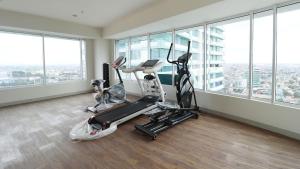 a gym with two exercise bikes in a room with windows at Papilukas Room Grand Kamala Lagoon - Studio East in Bekasi