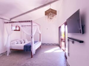 um quarto com uma cama de dossel e uma televisão em Kite Soul Pousada em Cumbuco