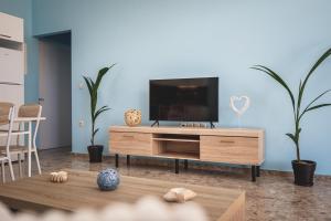 sala de estar con TV de pantalla plana en un centro de entretenimiento de madera en Natalia's Stay, en Thermisía