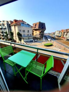 twee groene stoelen en een tafel op een balkon bij Zeezicht Sibeac Koksijde in Koksijde