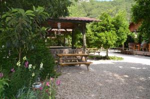 a wooden bench in a garden with a gazebo at Olympos Yakamoz Pansiyon in Olympos