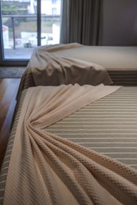 Una cama con una manta y una ventana en Hotel Comodoro, en Corvo