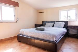 a bedroom with a bed in a room with two windows at Natural Mystic Hostel in Costa da Caparica