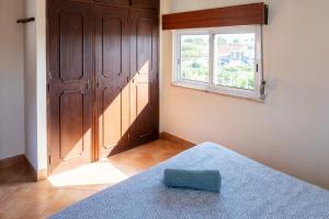 a bedroom with a window and a bed with a blue blanket at Natural Mystic Hostel in Costa da Caparica