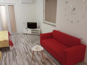 a living room with a red couch and a clock on the wall at Studio apartman Matković in Imotski
