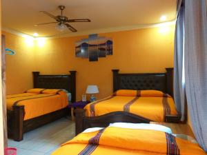two beds in a room with yellow walls at Hospedaje El Viajero in Panajachel
