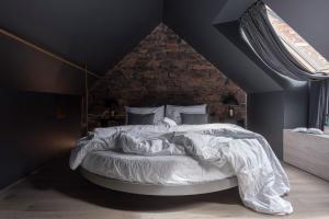 Ce lit se trouve dans une chambre dotée d'un mur en briques. dans l'établissement Bōheme House, à Kaunas