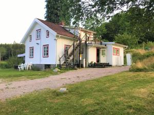 Casa blanca pequeña con porche y escalera en Björsjöås Vildmark - room in the main house, en Olofstorp