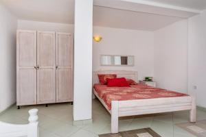 a white bedroom with a bed with a red blanket at Apartmani LIRA in Sutomore