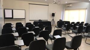 an empty room with chairs and a white screen at Buriti Hotel in Jataí