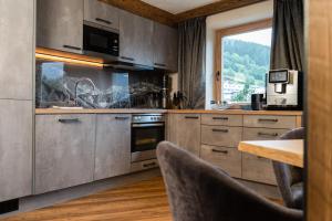 a kitchen with gray cabinets and a table with chairs at Chalet EDELWEISS - Private Wellness with Whirlpool & Sauna in Ladis