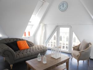 a living room with a couch and a table and a clock at Holiday Home Ieper Market Square in Ieper