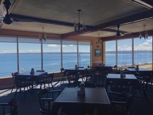 Admiral Digby Inn Restaurant and Cottages في ديغبي: مطعم به طاولات وكراسي ومطل على المحيط