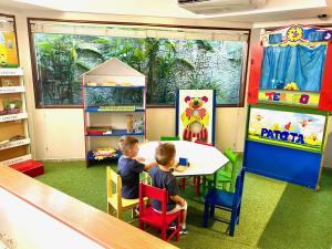 zwei Kinder, die an einem Tisch im Spielzimmer sitzen in der Unterkunft Kastel Manibu Recife - Boa Viagem in Recife