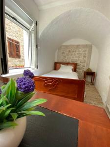 a bedroom with a bed and a vase of purple flowers at Apartment Ozana in Kotor