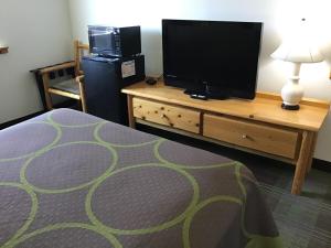 a bedroom with a tv and a dresser with a bed at Super 8 by Wyndham Powell in Powell