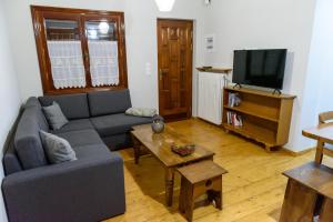 a living room with a couch and a tv at ΔΗΜΗΤΣΑΝΑΣ ΤΟΠΟΣ Νύμφη Αγνώ in Dhimitsana