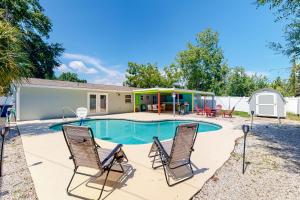 a swimming pool with two chairs and a house at Pinellas Park Cottage in St. Petersburg