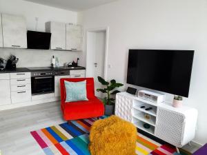 ein Wohnzimmer mit einem roten Stuhl und einem Flachbild-TV in der Unterkunft PB Ferienwohnungen - FeWo 6 - Stilvoll eingerichtetes Apartment im Herzen Senftenbergs in Senftenberg