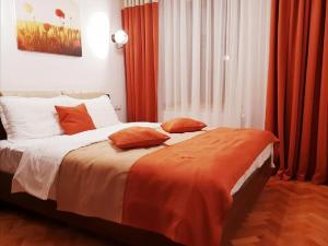 Studio Piata Mare apartments في سيبيو: غرفة نوم بسرير كبير مع ستائر برتقالية