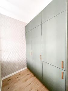 um quarto com armários cinzentos e piso de madeira em SuperApart Omulewska em Varsóvia