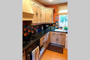 a kitchen with wooden cabinets and a stove top oven at Cosy 2 bed house near Peak District in Greenhill
