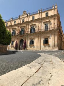 a large building with a clock on the side of it at Landolina Palace Hotel in Noto